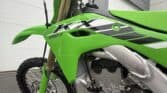 Green Kawasaki KX250X dirt bike with black and white graphics.