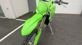 Bright green Kawasaki KX250X dirt bike in showroom setting.